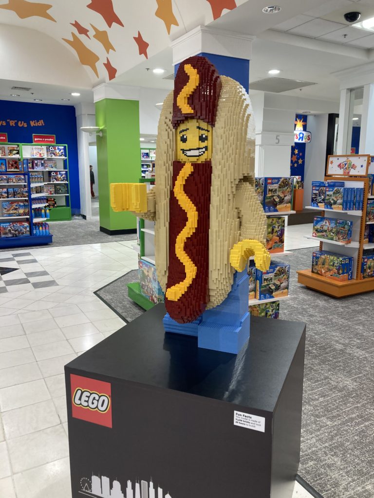 A large man in a hot dog suit that is built out of Legos.