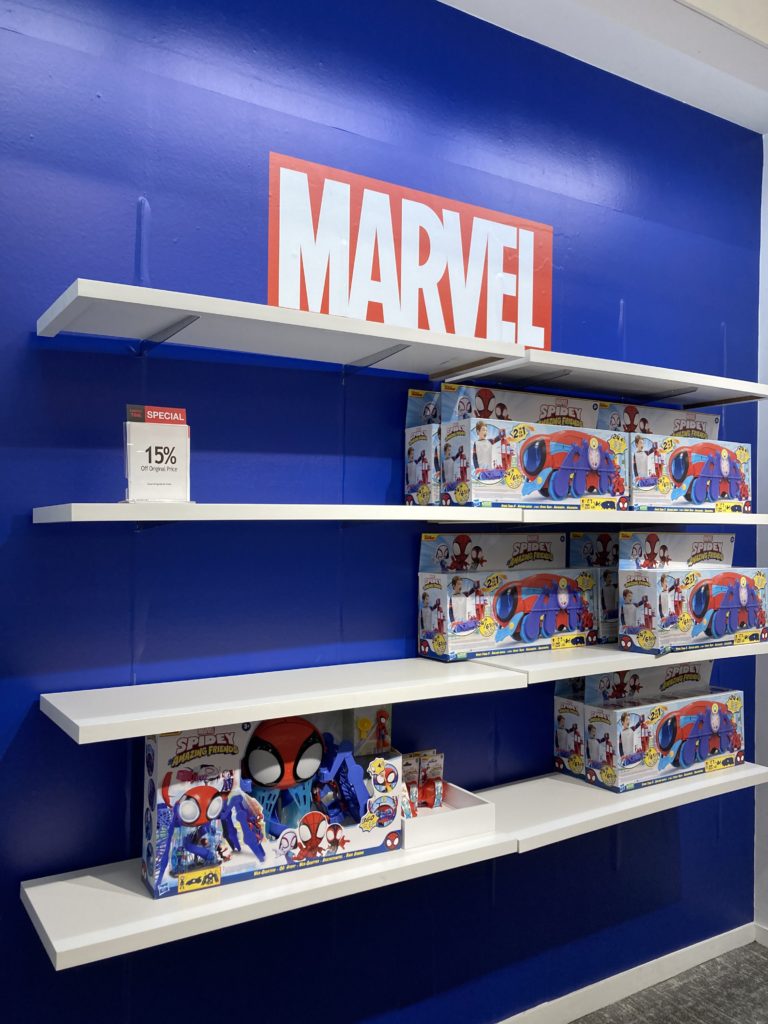 A set of shelves half full with Marvel toys.