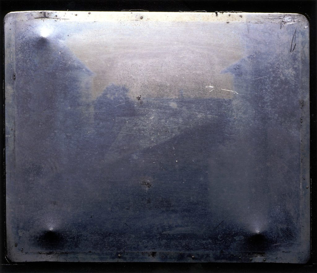 An image of the Niépce Heliograph. A pewter plate shows the dark outline of some buildings and the sky.